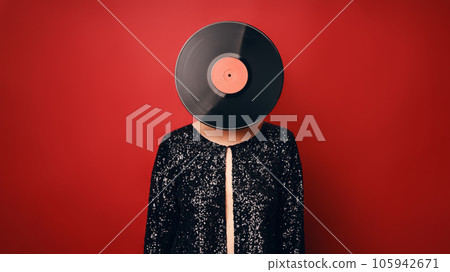 Woman in sequin dress with vinyl record head isolated over red background. 105942671