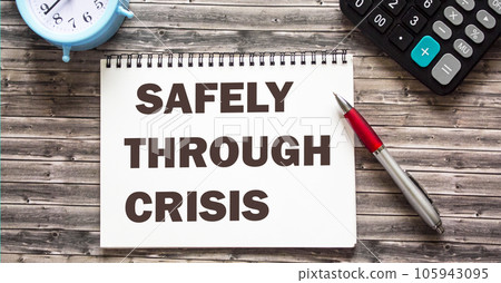 Calculator, alarm clock and pen. The text on the notebook is SAFELY THROUGH CRISIS. 105943095