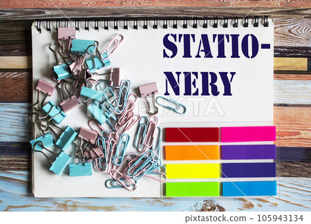 Colorful paper clips and stickers on a wooden background and with the text stationery 105943134
