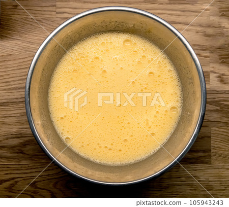 whipped eggs in metal bowl 105943243
