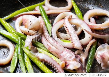 A cooking scene where squid (boiled squid) and garlic sprouts are fried in a frying pan. A cooking scene where squid (boiled squid) and garlic sprouts are fried in a frying pan. 105943507