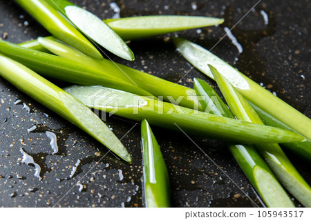 A cooking scene where garlic sprouts (diagonally cut) are fried in a frying pan. 105943517