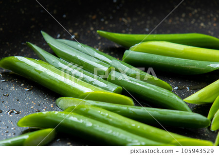 A cooking scene where garlic sprouts (diagonally cut) are fried in a frying pan. 105943529