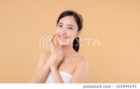 Beautiful girl asian model touching fresh glowing hydrated facial skin on beige background closeup. Beauty face young woman with natural makeup and healthy skin portrait. Skin care concept Beautiful girl asian model touching fresh glowing hydrated facial skin on beige background closeup. Beauty face young woman with natural makeup and healthy skin portrait. Skin care concept 105944245