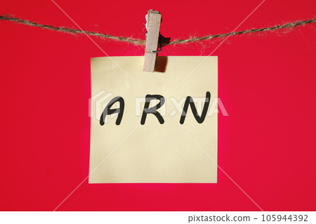 ARN as Account Reference Number written text on a yellow sticker hanging on a rope with clothespins on a red background 105944392