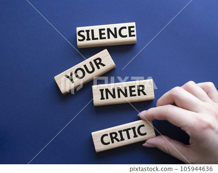 Silence your inner critic symbol. Wooden blocks with words Silence your inner critic. Beautiful deep blue background. Businessman hand. Business and Silence your inner critic concept. Copy space. 105944636
