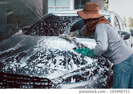 Woman worker washing car at car station outdoors with foam and yellow sponge. 105946751