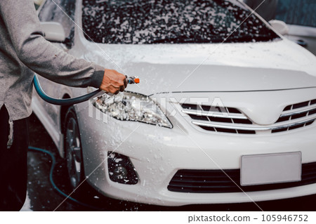 Unidentified man washing a car with high pressure foam. 105946752