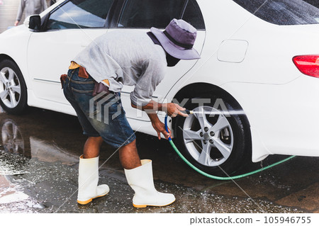 Unidentified man washing car on carwash station using high pressure water. Unidentified man washing car on carwash station using high pressure water. 105946755