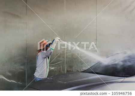 Worker washing auto with high pressure water jet in car wash. Worker washing auto with high pressure water jet in car wash. 105946756