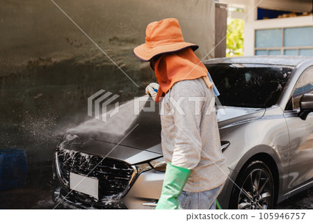 Unidentified man washing car on carwash station using high pressure water. Unidentified man washing car on carwash station using high pressure water. 105946757