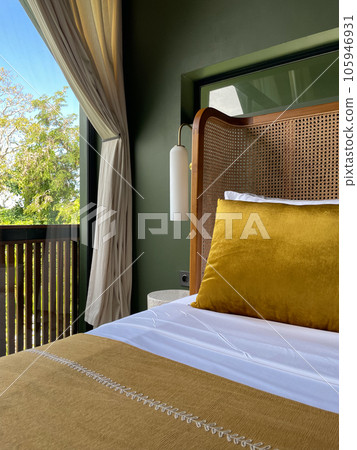 Bed with decorative pillows and a mustard-colored bedspread Bed with decorative pillows and a mustard-colored bedspread 105946931