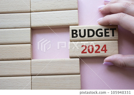 Budget 2024 symbol. Wooden blocks with words Budget 2024. Beautiful pink background. Businessman hand. Business and Budget 2024 concept. Copy space. 105948331