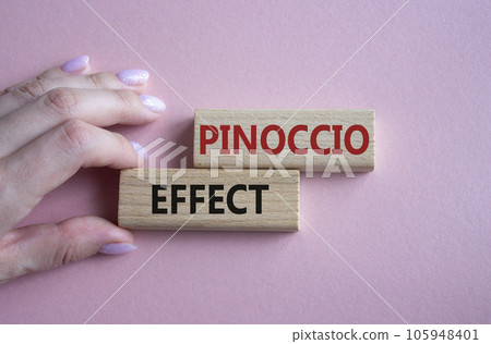 Pinoccio Effect symbol. Concept word Pinoccio Effect on wooden blocks. Businessman hand. Beautiful pink background. Business and Pinoccio Effect concept. Copy space 105948401