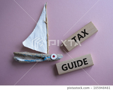 Tax Guide symbol. Concept word Tax Guide on wooden blocks. Beautiful pink background. Business and Tax Guide concept. Copy space 105948481