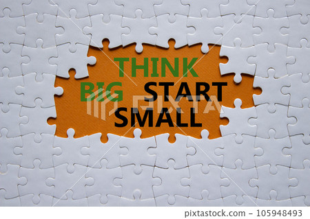 Think big start small symbol. Concept words Think big start small on white puzzle. Beautiful orange background. Business and Think big start small concept. Copy space 105948493