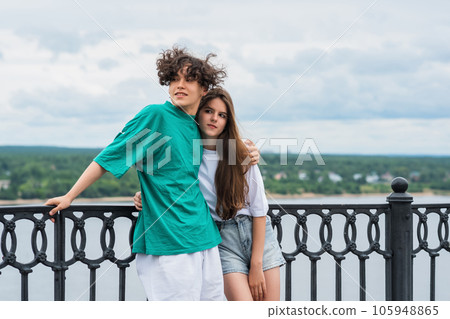couple of young people hugging against a blurred river landscape couple of young people hugging against a blurred river landscape 105948865