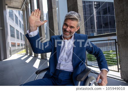 Gray haired disabled man wearing official style suit in wheelchair, raising palm, giving high five Gray haired disabled man wearing official style suit in wheelchair, raising palm, giving high five 105949010