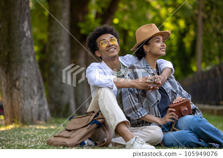 Young cute couple sitting on the grass and looking romantic Young cute couple sitting on the grass and looking romantic 105949076