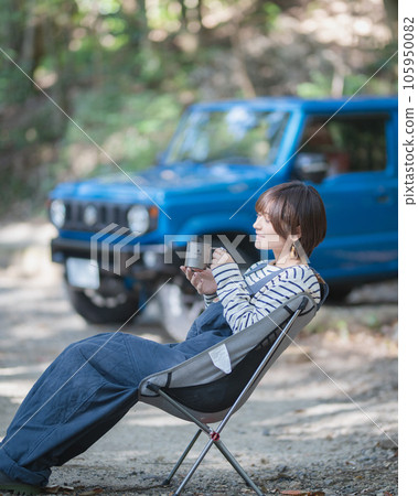 A woman sitting on an outdoor chair and drinking a drink with a blue car in the background A woman sitting on an outdoor chair and drinking a drink with a blue car in the background 105950082