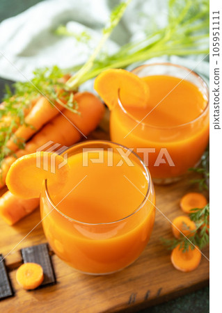 Carrot juice in a glass and fresh carrots with leaves on a stone table. Carrot healthy juice for detox. Healthy vegan vegetarian drink. Carrot juice in a glass and fresh carrots with leaves on a stone table. Carrot healthy juice for detox. Healthy vegan vegetarian drink. 105951111