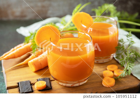 Carrot juice in a glass and fresh carrots with leaves on a stone table. Carrot healthy juice for detox. Healthy vegan vegetarian drink. Carrot juice in a glass and fresh carrots with leaves on a stone table. Carrot healthy juice for detox. Healthy vegan vegetarian drink. 105951112