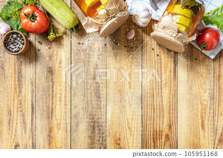 Healthy homemade fermented food. Marinated zucchini (courgette) in tomato sauce on a rustic table. Home economics, autumn harvest preservation. View from above. Copy space. 105951168
