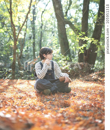 戶外女孩坐在落葉中，側視 105951318