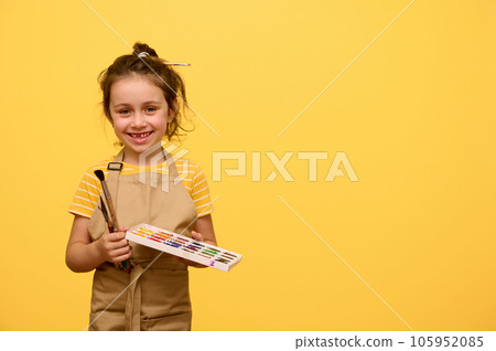 Beautiful kid girl with paint brush and watercolour palette, inspired little painter, artist smiles looking at camera 105952085