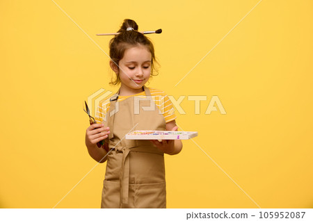 Portrait on yellow background of a cute little kid girl with painting tools, isolated over yellow studio background Portrait on yellow background of a cute little kid girl with painting tools, isolated over yellow studio background 105952087