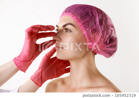Preparation before rhinoplasty. Young woman visiting surgeon before operation against white studio background 105952319