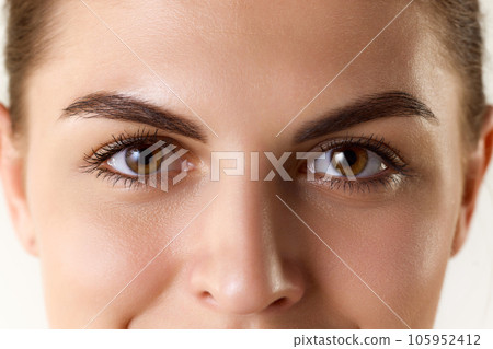 Brown eyes. Close up portrait of beautiful young girl looking at camera. Natural looking lashes and eyebrows 105952412