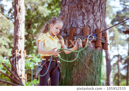 A child in a forest adventure park made of ropes. 105952535