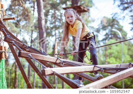 A child in a forest adventure park made of ropes. A child in a forest adventure park made of ropes. 105952547
