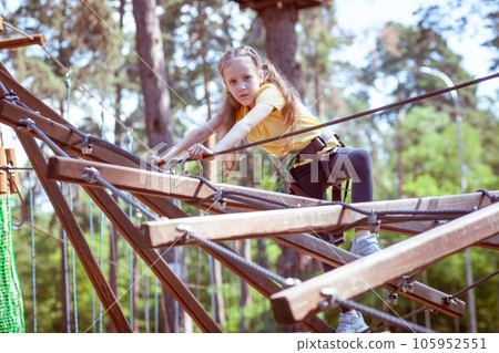 A child in a forest adventure park made of ropes. 105952551