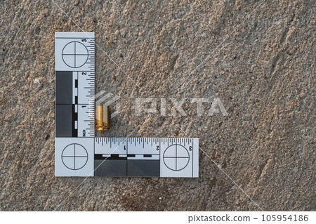 One crime scene evidence ruler on the street after a gun shooting brass bullet shell casing 9mm handgun pistol One crime scene evidence ruler on the street after a gun shooting brass bullet shell casing 9mm handgun pistol 105954186