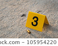 One yellow crime scene evidence marker on the street after a gun shooting brass bullet shell casing 9mm handgun pistol 105954220