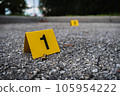 A group of yellow crime scene evidence markers on the street after a gun shooting brass bullet shell casing rifle 105954222