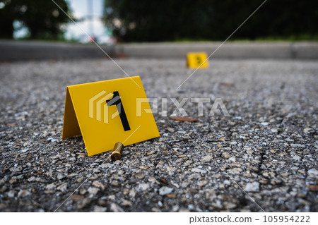 A group of yellow crime scene evidence markers on the street after a gun shooting brass bullet shell casing rifle A group of yellow crime scene evidence markers on the street after a gun shooting brass bullet shell casing rifle 105954222