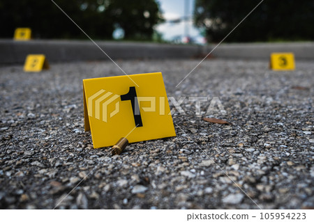 A group of yellow crime scene evidence markers on the street after a gun shooting brass bullet shell casing rifle A group of yellow crime scene evidence markers on the street after a gun shooting brass bullet shell casing rifle 105954223