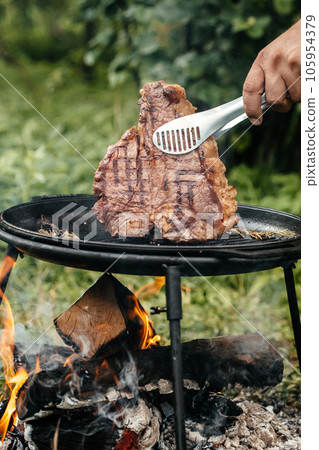 meat steak. Fresh raw Prime Black Angus beef steak cooking on flaming grill with smoke 105954379