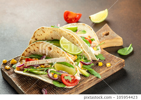 Tacos with grilled chicken, avocado, fresh tomatoes, limes. mexican burritos on a wooden board. banner, menu, recipe place for text, top view Tacos with grilled chicken, avocado, fresh tomatoes, limes. mexican burritos on a wooden board. banner, menu, recipe place for text, top view 105954423