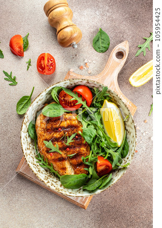 Fresh green salad with grilled chicken fillet, tomatoes, avocado, lemon on light background. Diet Concept. Top view copy space Fresh green salad with grilled chicken fillet, tomatoes, avocado, lemon on light background. Diet Concept. Top view copy space 105954425