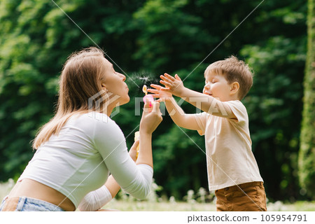 Family weekend of a mother and her little son. Loving parent having fun blowing soap bubbles with a three year old boy Family weekend of a mother and her little son. Loving parent having fun blowing soap bubbles with a three year old boy 105954791