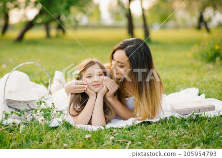 A beautiful mother and her daughter are lying on the beach and relaxing in the fresh air 105954793