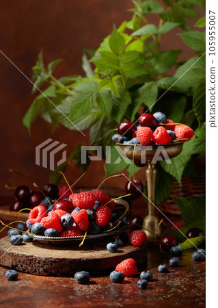 Berries with leaves on an old brown table. 105955007