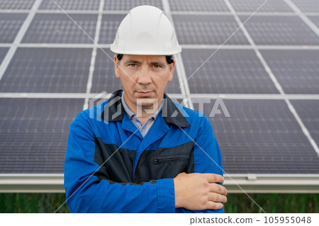 Service Engineer man standing with arms crossed in front of solar panels. Technician maintenance solar cells on Solar Energy Plant under morning sunlight. Technology solar energy renewable 105955048