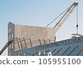 A yellow crane behind the concrete frame of a new building at a construction site during a sunny day 105955100