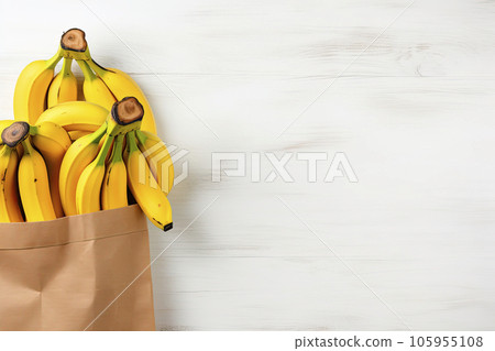 bananas in a recycled paper bag on white wooden table. Top view. Copy space 105955108