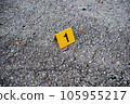 One yellow crime scene evidence marker on the street after a gun shooting brass bullet shell casing 9mm handgun pistol 105955217